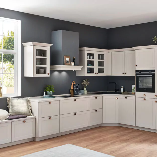 Cremefarbene Landhausküche in L-Form mit blauer Wand.